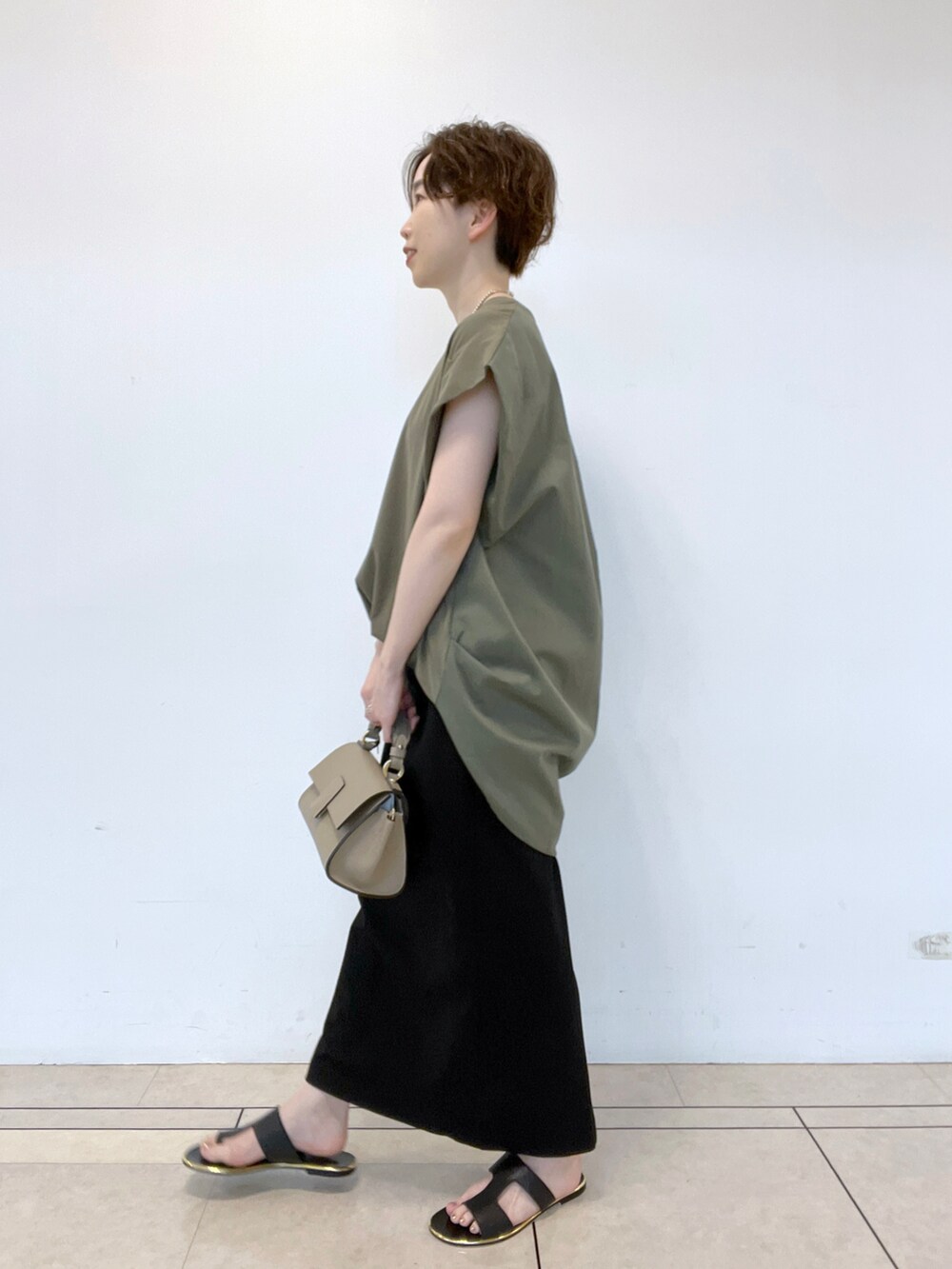ブラック系のサンダル、グリーン系のTシャツ/カットソー、ブラック系のスカートを着用したレディースの春コーディネートの2枚目の写真