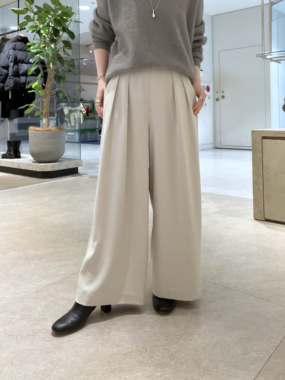 グレー系のニット/セーター、グレー系のスラックス、ベージュ系のハンドバッグを着用したレディースの冬コーディネートの7枚目の写真