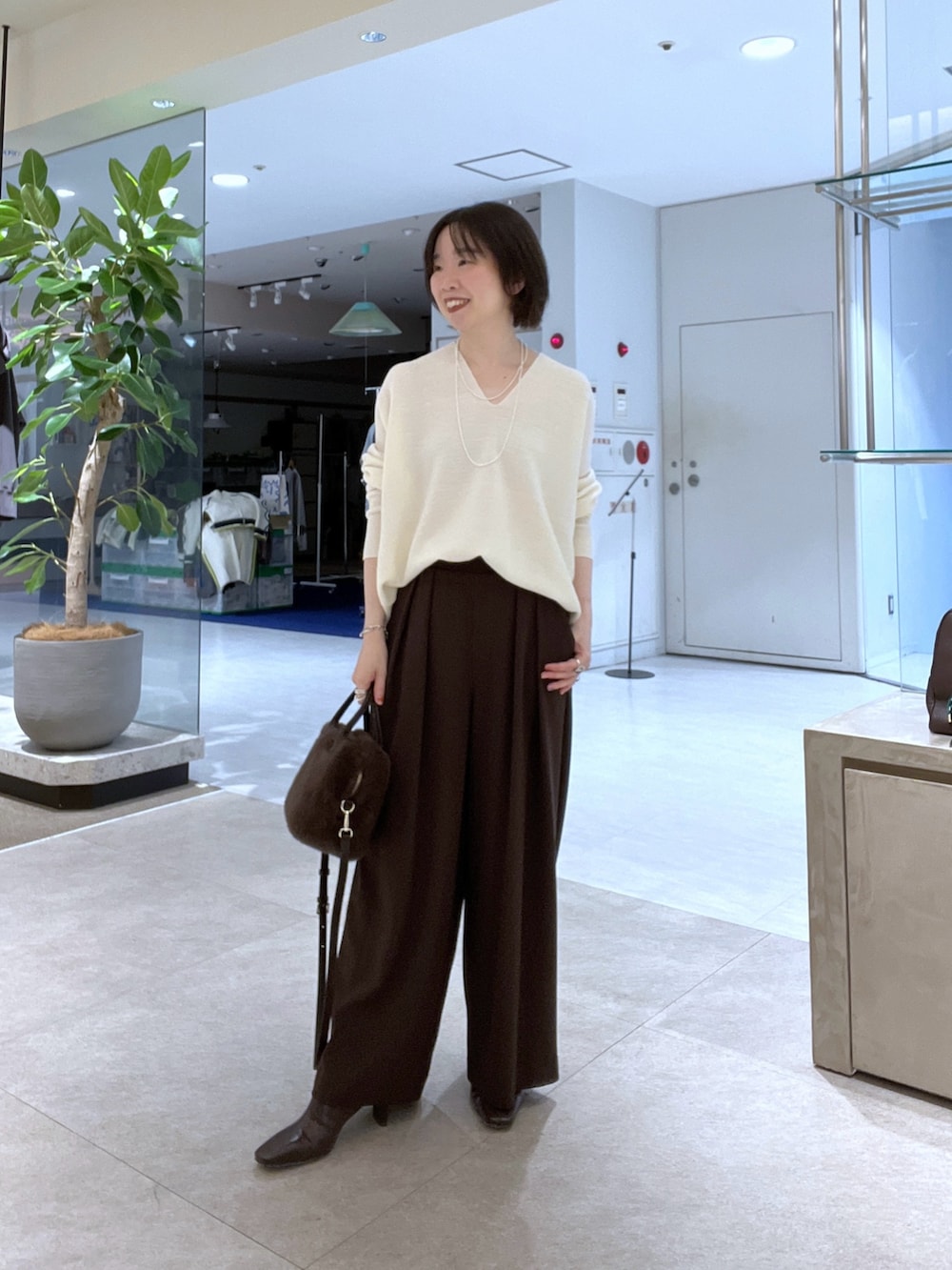 イエロー系のその他アウター、ホワイト系のニット/セーター、ブラウン系のスラックスを着用したレディースの秋コーディネートの5枚目の写真