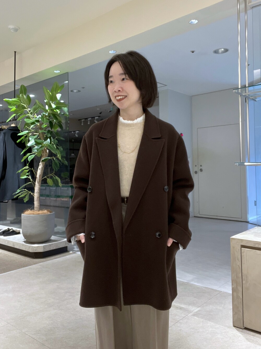 ブラウン系のトートバッグ、ベージュ系のスラックス、ブラウン系のブーツを着用したレディースの秋コーディネートの4枚目の写真