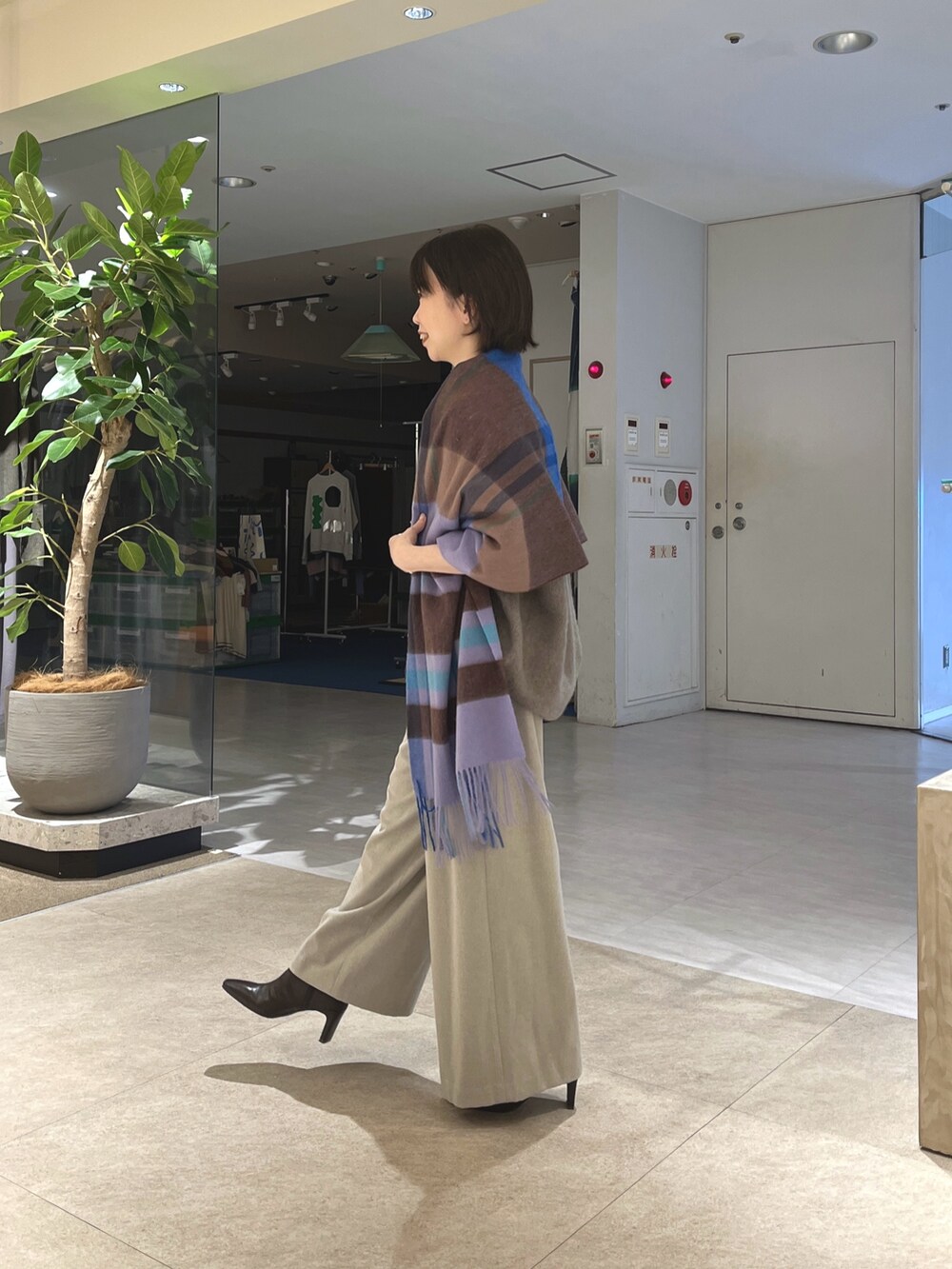グレー系のニット/セーター、ベージュ系のスラックス、ブラウン系のボストンバッグを着用したレディースの秋コーディネートの2枚目の写真