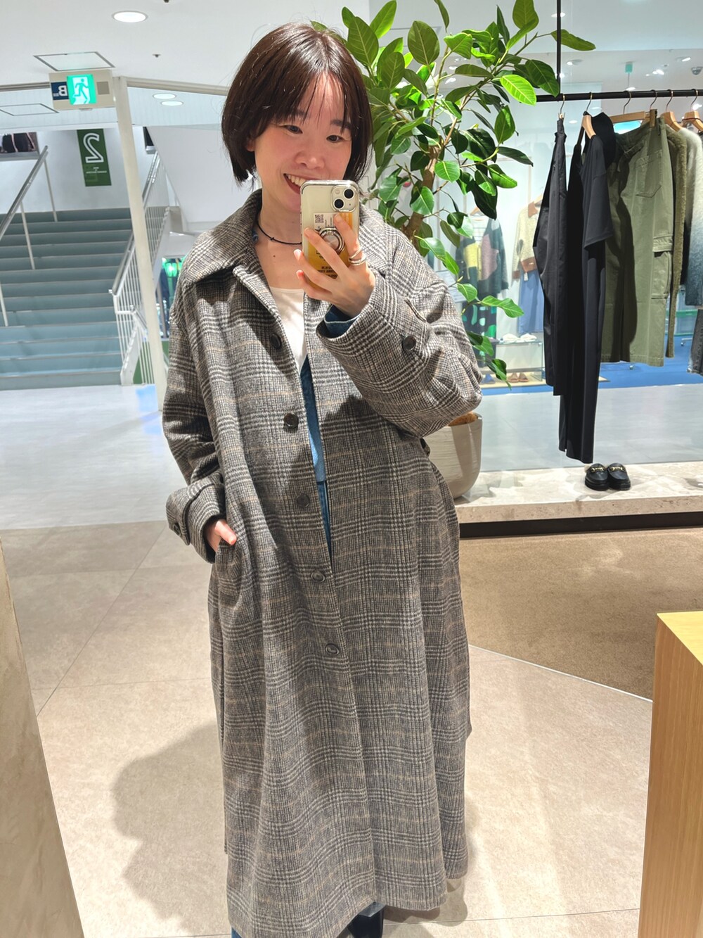 グレー系のステンカラーコート、ブルー系のデニムパンツ、ホワイト系のTシャツ/カットソーを着用したレディースの秋コーディネートの2枚目の写真