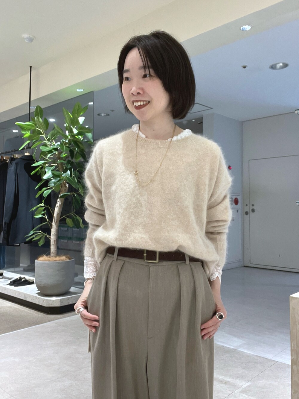 ベージュ系のスラックス、ブラウン系のトートバッグ、ブラウン系のブーツを着用したレディースの秋コーディネートの4枚目の写真