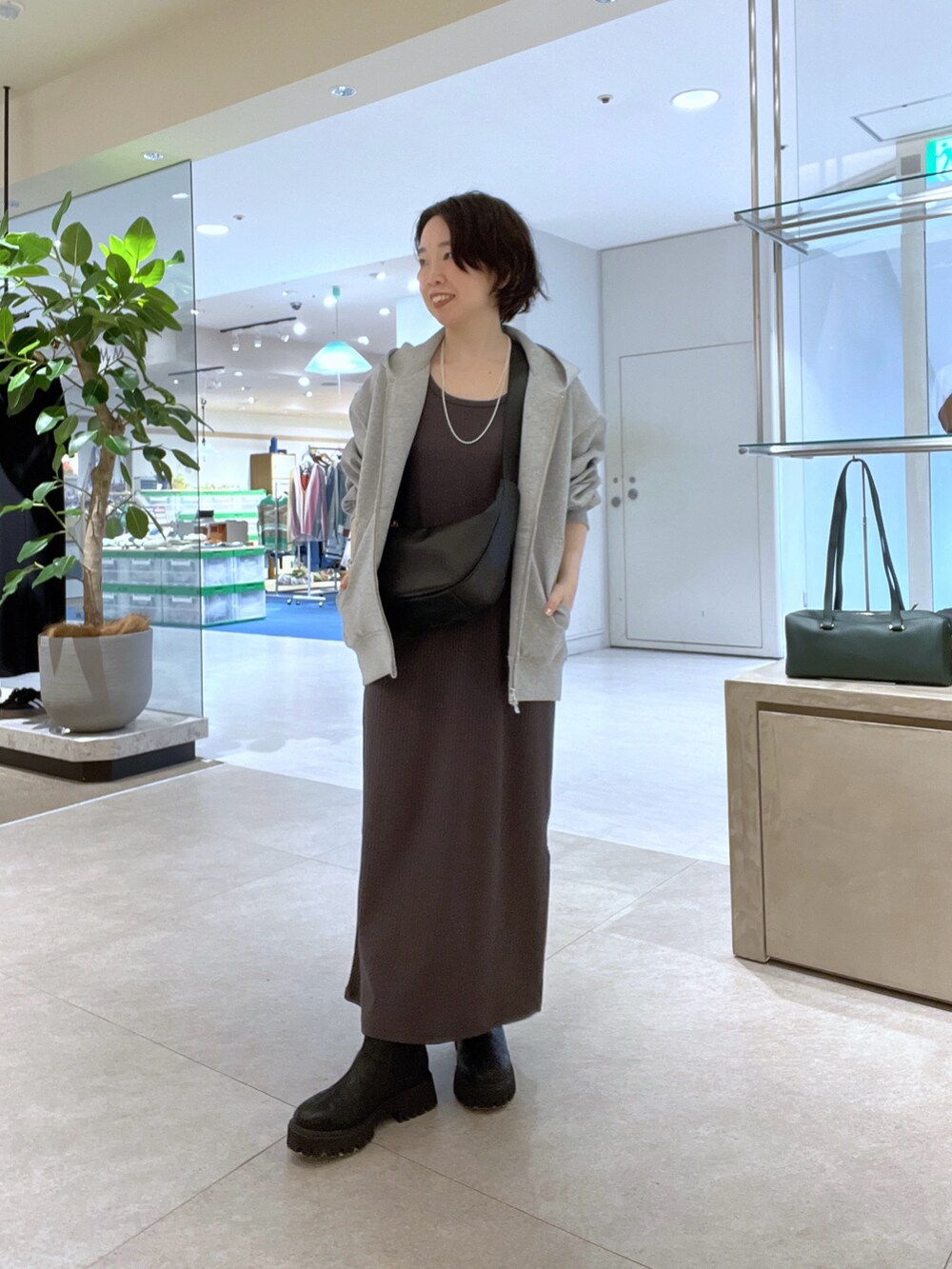 ブラウン系のワンピース、ブラック系のショルダーバッグ、ブラック系のブーツを着用したレディースの秋コーディネートの4枚目の写真