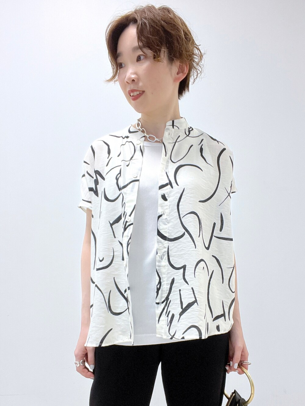 ブラック系のショルダーバッグ、ホワイト系のシャツ/ブラウス、ホワイト系のタンクトップを着用したレディースの春コーディネートの3枚目の写真