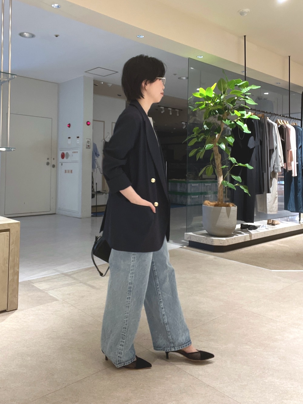 ブルー系のデニムパンツ、ブラック系のパンプス、ブラック系のボストンバッグを着用したレディースの夏コーディネートの2枚目の写真