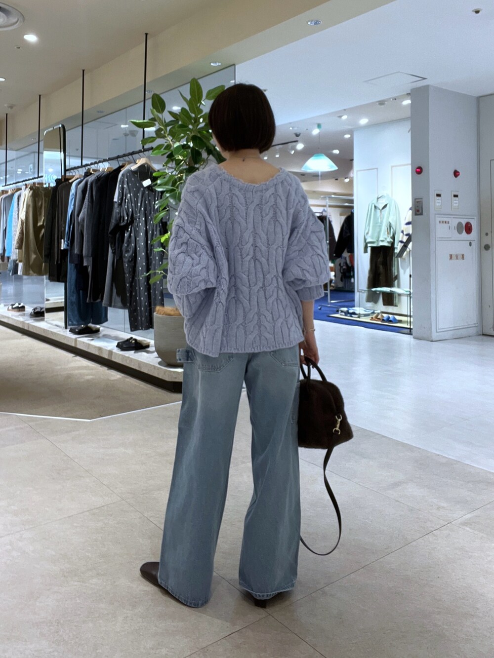 ブルー系のデニムパンツ、ブラウン系のボストンバッグ、ブラウン系のブーツを着用したレディースの秋コーディネートの8枚目の写真