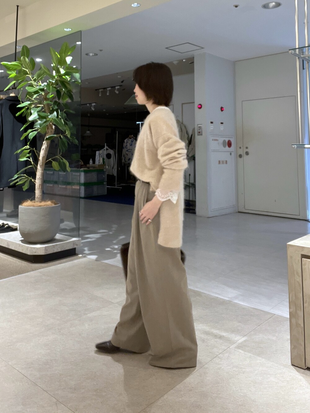 ブラウン系のトートバッグ、ベージュ系のスラックス、ブラウン系のブーツを着用したレディースの秋コーディネートの8枚目の写真