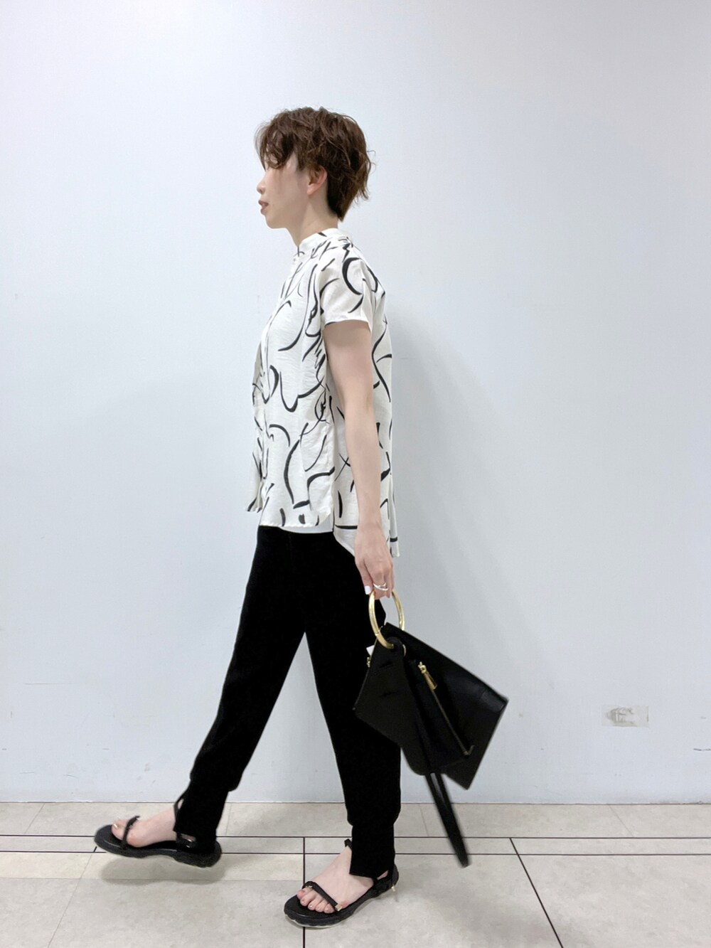 ブラック系のショルダーバッグ、ホワイト系のシャツ/ブラウス、ホワイト系のタンクトップを着用したレディースの春コーディネートの2枚目の写真