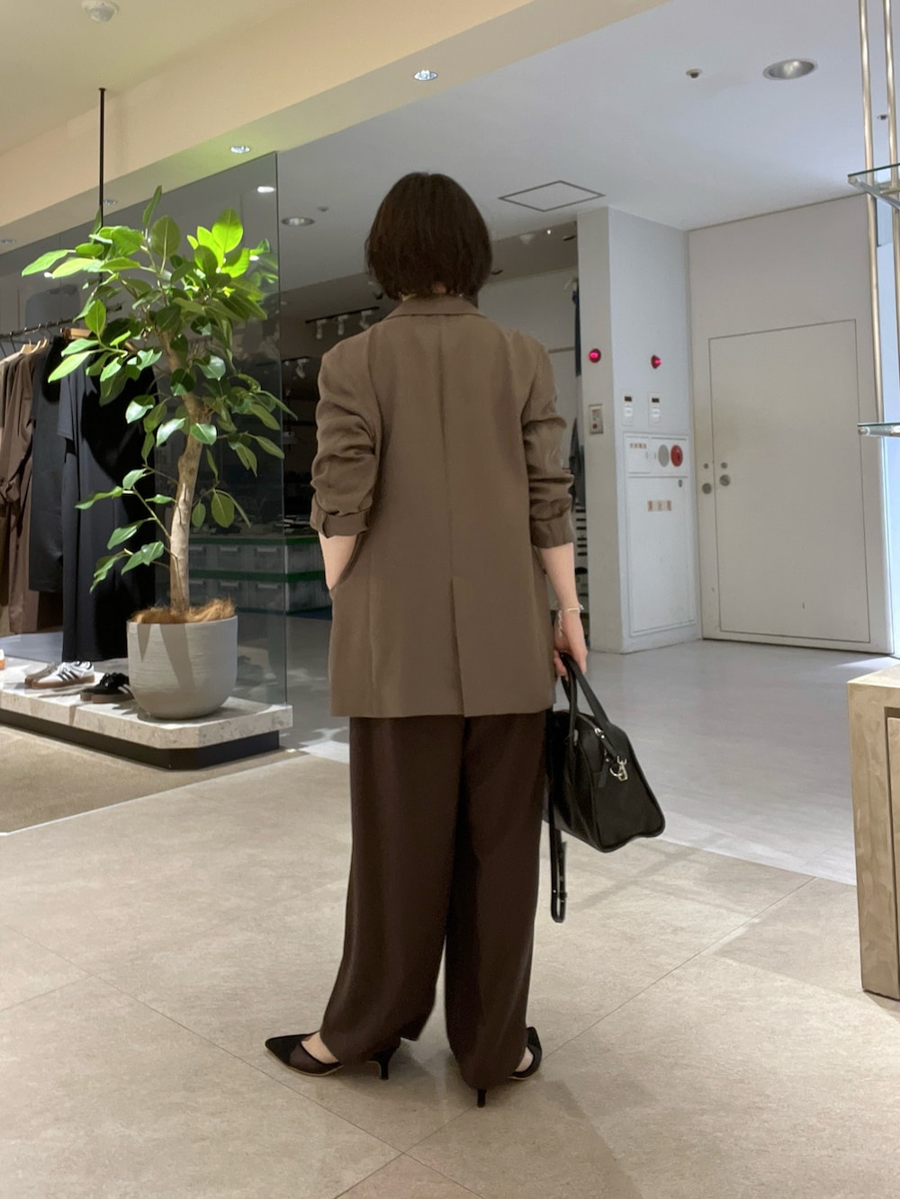 ブラウン系のスラックス、ブラック系のパンプス、ブラウン系のTシャツ/カットソーを着用したレディースの秋コーディネートの4枚目の写真