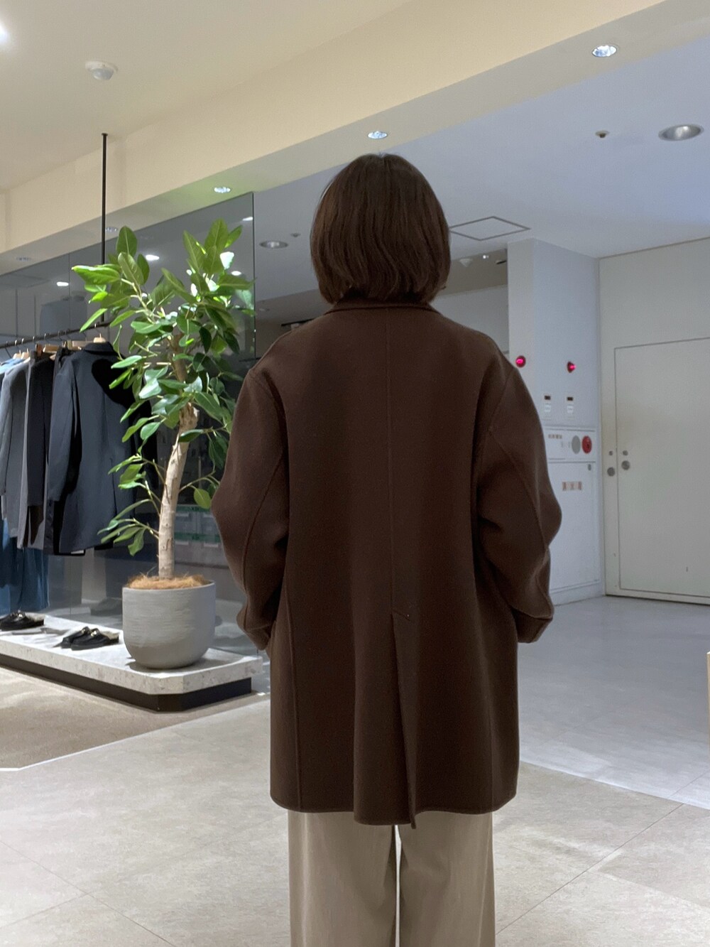 ブラウン系のトートバッグ、ベージュ系のスラックス、ブラウン系のブーツを着用したレディースの秋コーディネートの6枚目の写真