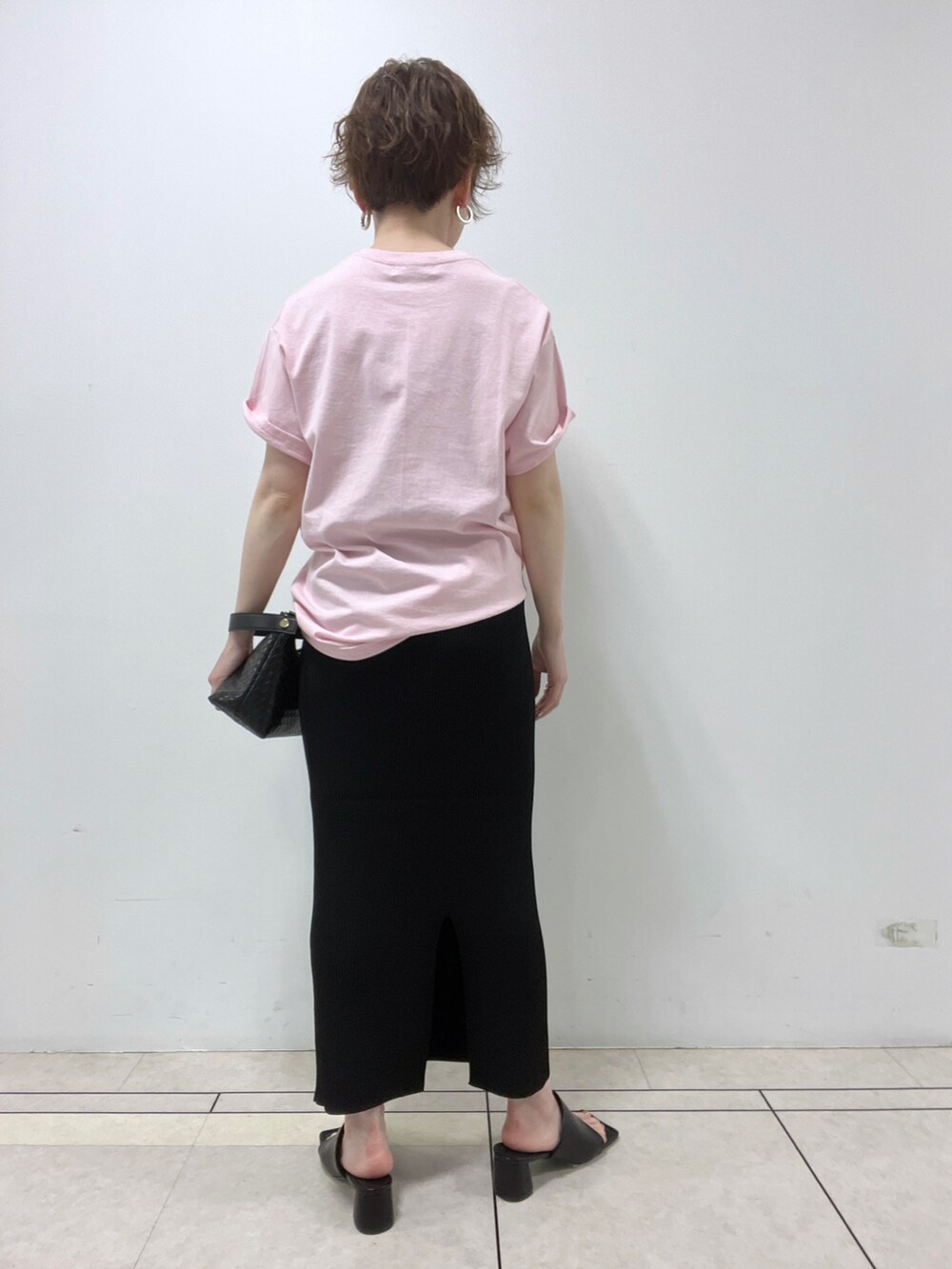 ピンク系のTシャツ/カットソー、ブラック系のスカート、ブラック系のハンドバッグを着用したレディースの春コーディネートの3枚目の写真