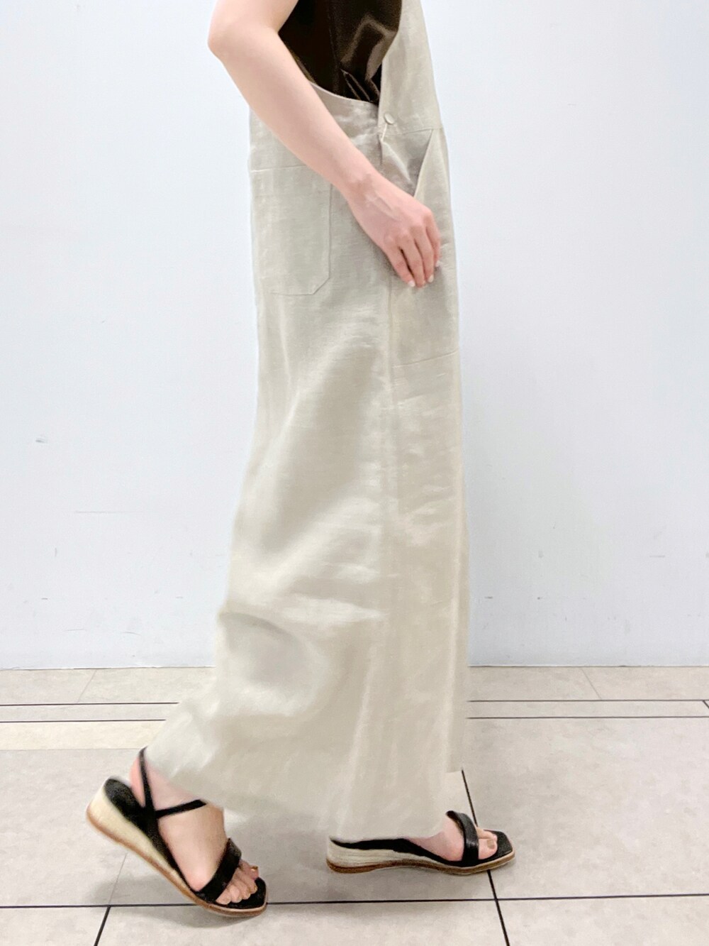 ブラウン系のトートバッグ、ベージュ系のジャンパースカート、グリーン系のTシャツ/カットソーを着用したレディースの夏コーディネートの2枚目の写真