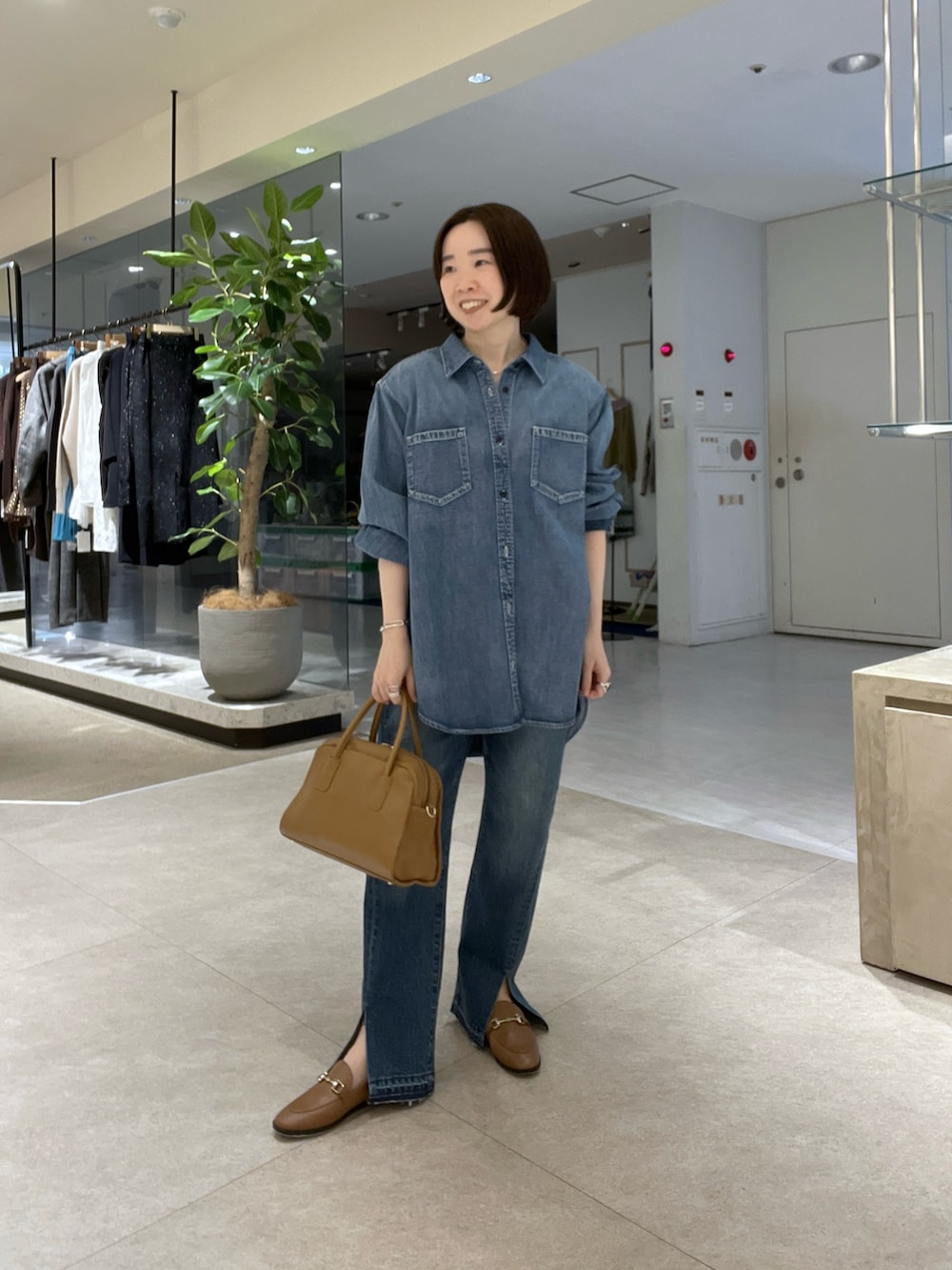 ブルー系のシャツ/ブラウス、ブルー系のデニムパンツ、イエロー系のボストンバッグを着用したレディースの冬コーディネートの2枚目の写真