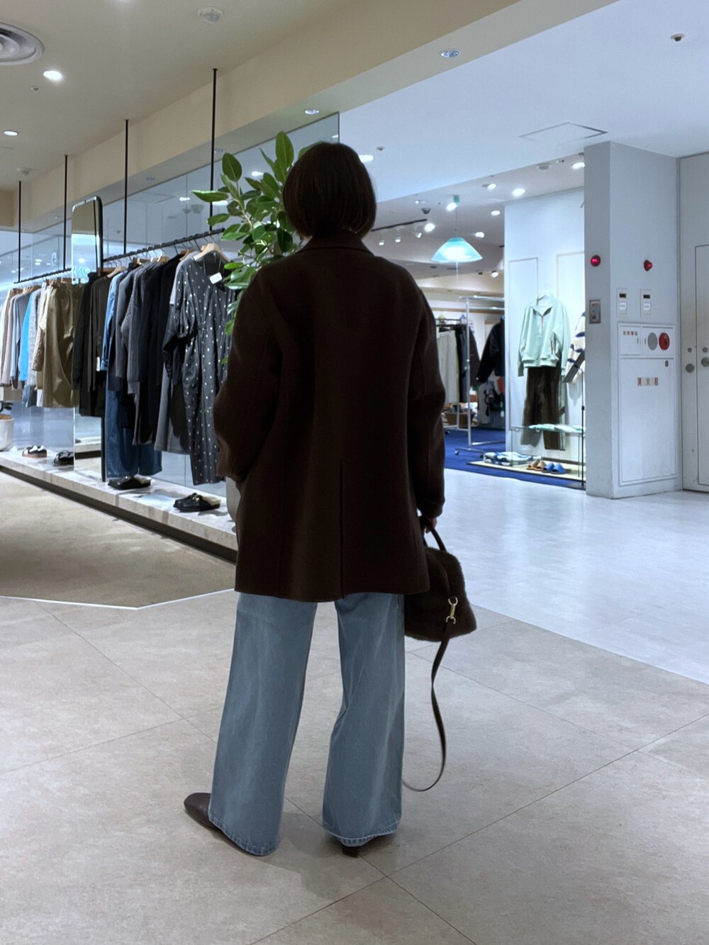 ブルー系のデニムパンツ、ブラウン系のボストンバッグ、ブラウン系のブーツを着用したレディースの秋コーディネートの3枚目の写真