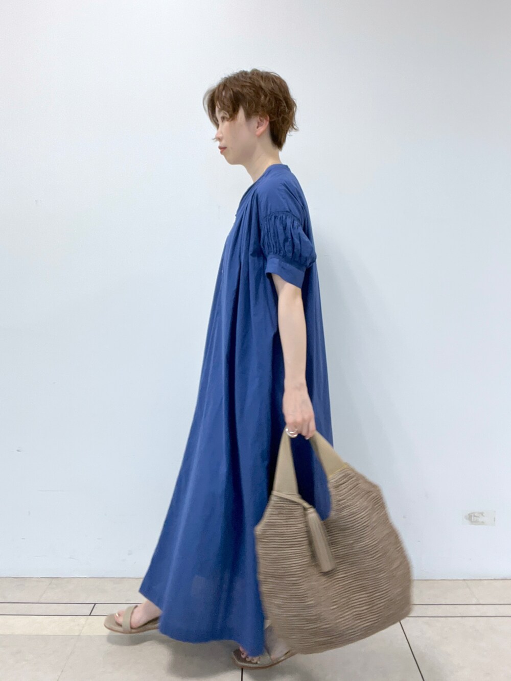 ブルー系のワンピース、グレー系のかごバッグ、ベージュ系のサンダルを着用したレディースの春コーディネートの2枚目の写真