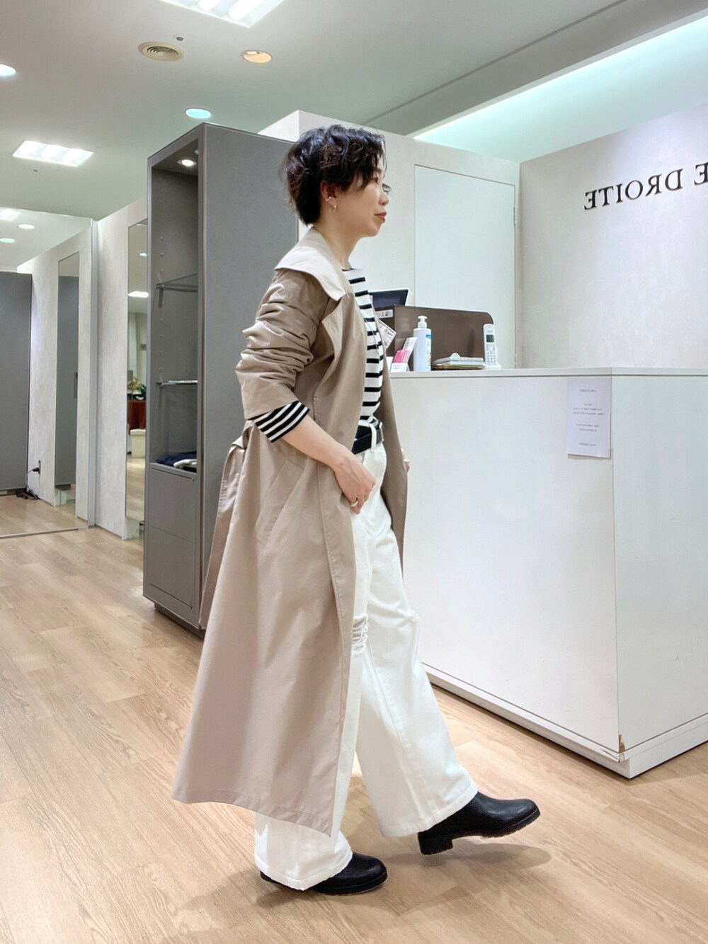 ホワイト系のデニムパンツ、ベージュ系のトレンチコート、ブラック系のTシャツ/カットソーを着用したレディースの冬コーディネートの3枚目の写真