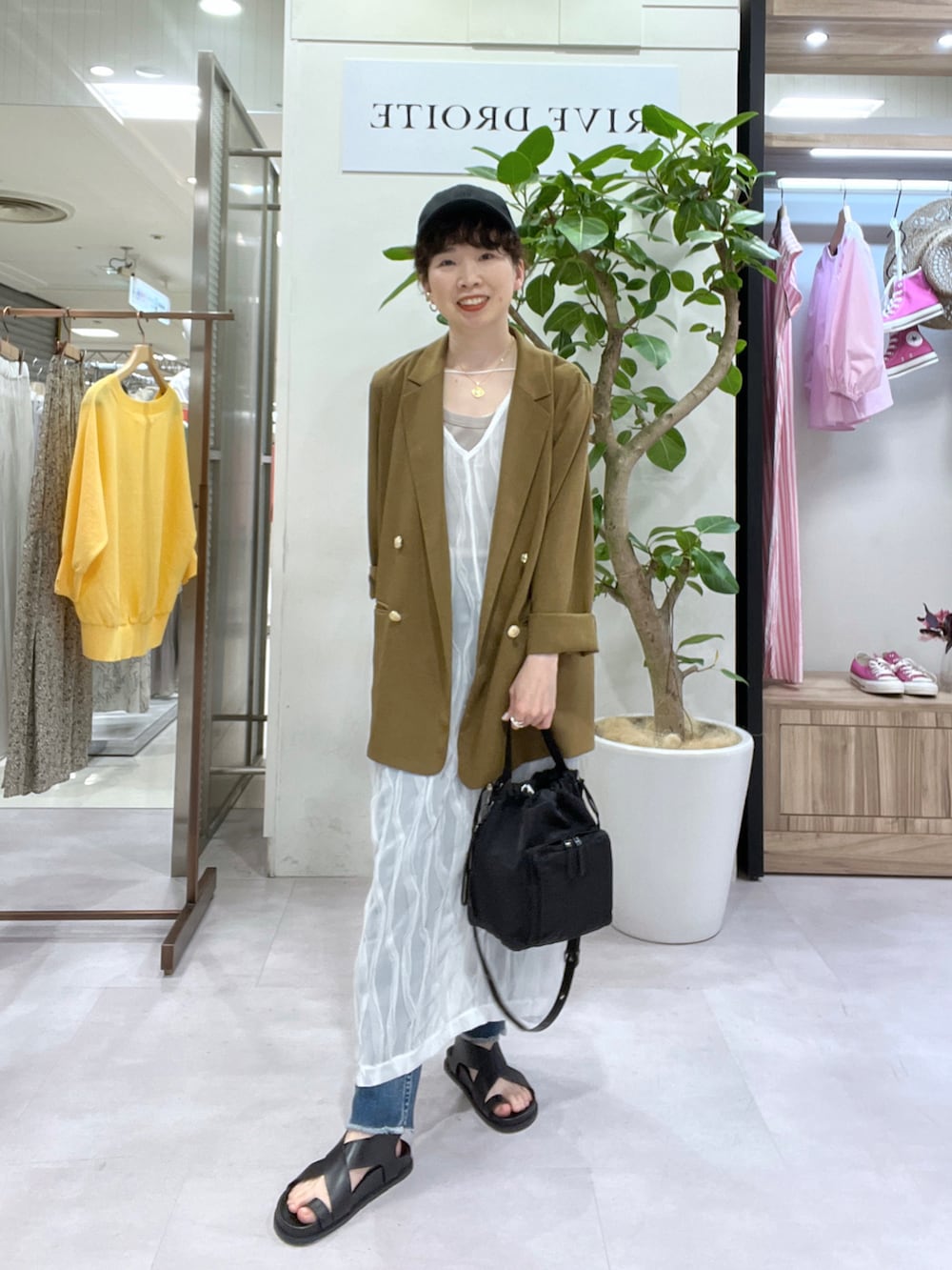 ブルー系のデニムパンツ、ブラウン系のテーラードジャケット、ベージュ系のタンクトップを着用したレディースの春コーディネートの2枚目の写真