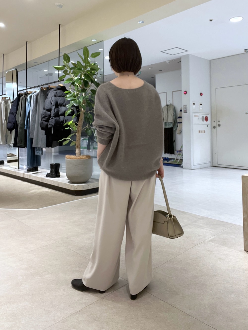 グレー系のニット/セーター、グレー系のスラックス、ベージュ系のハンドバッグを着用したレディースの冬コーディネートの2枚目の写真