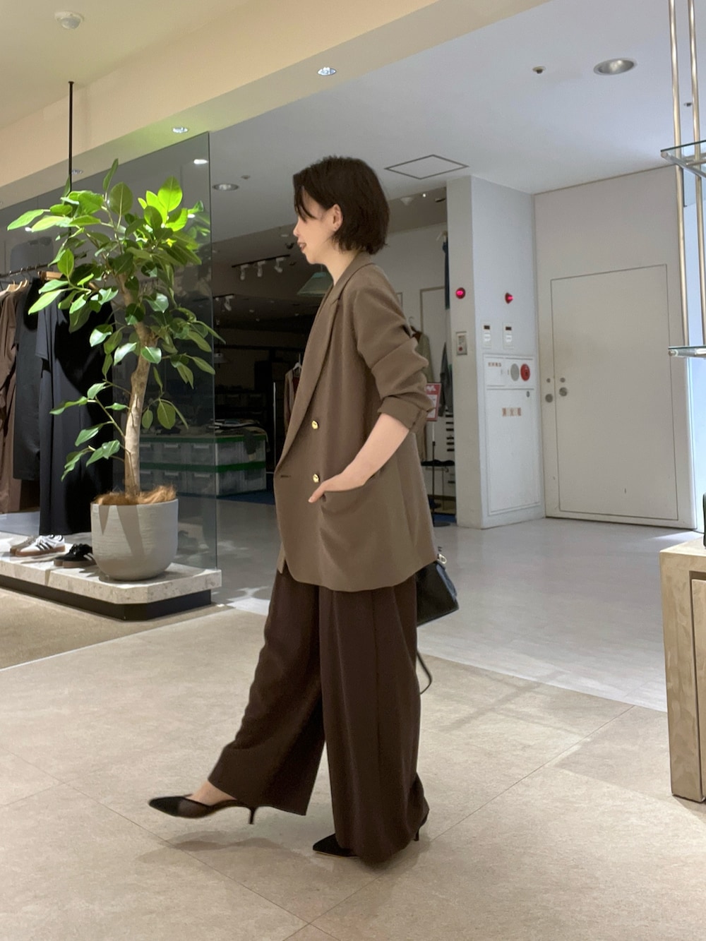 ブラウン系のスラックス、ブラック系のパンプス、ブラウン系のTシャツ/カットソーを着用したレディースの秋コーディネートの3枚目の写真