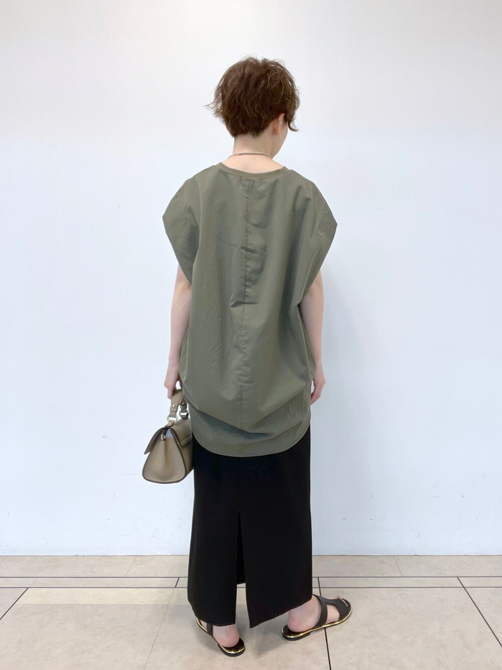 ブラック系のサンダル、グリーン系のTシャツ/カットソー、ブラック系のスカートを着用したレディースの春コーディネートの3枚目の写真