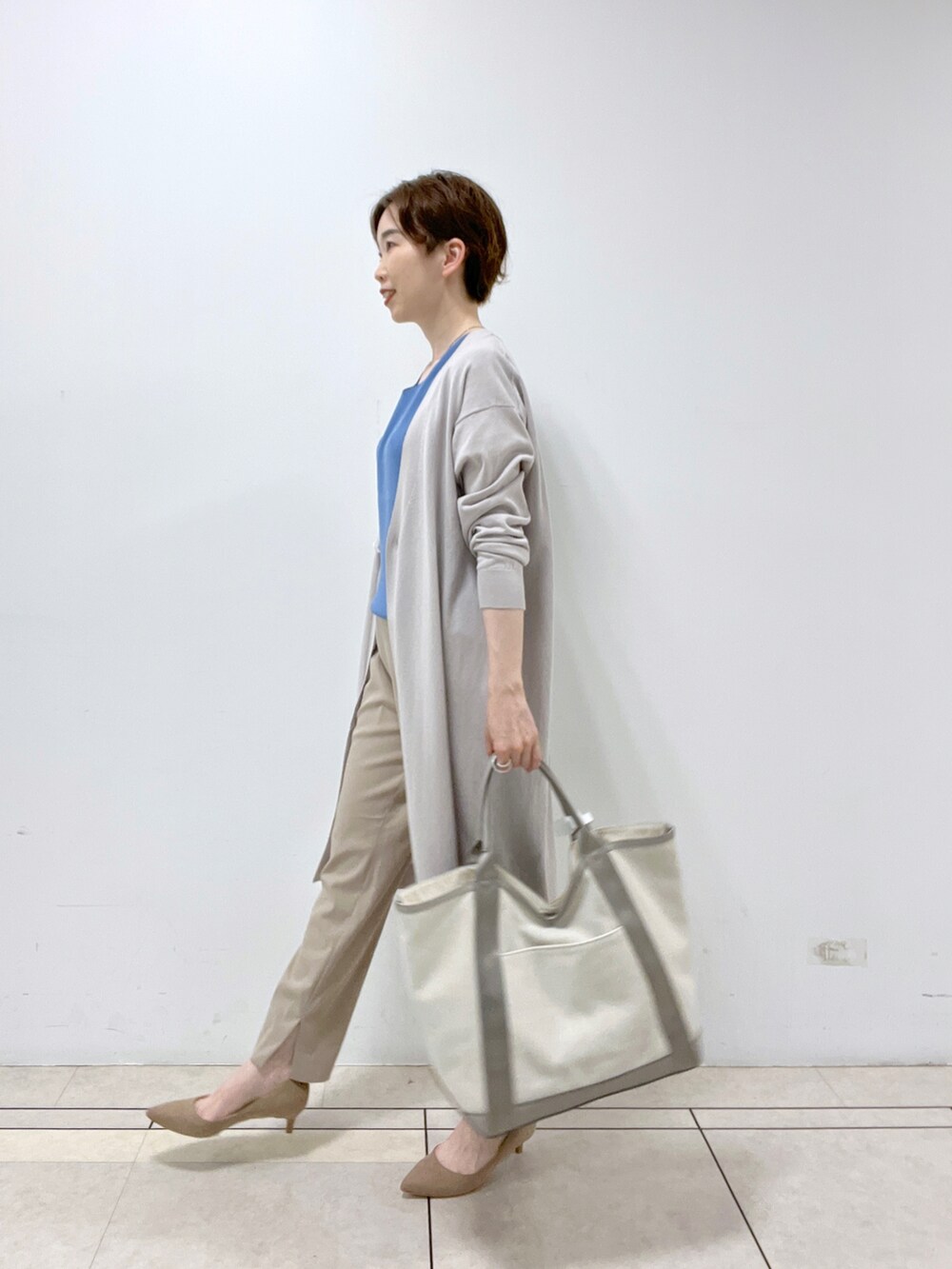 グレー系のトートバッグ、グレー系のカーディガン/ボレロ、ブルー系のニット/セーターを着用したレディースの夏コーディネートの2枚目の写真