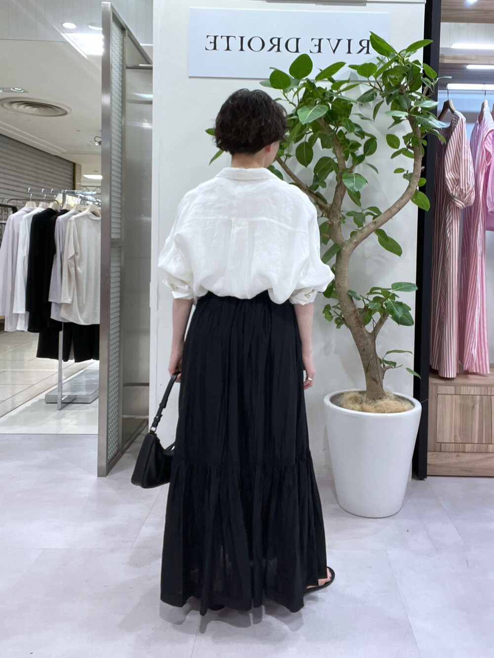 ブラック系のスカート、ホワイト系のシャツ/ブラウス、ホワイト系のTシャツ/カットソーを着用したレディースの春コーディネートの2枚目の写真