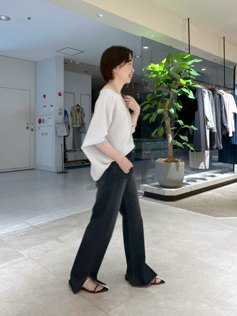 ブルー系のデニムパンツ、ブラック系のハンドバッグ、ブラック系のサンダルを着用したレディースの夏コーディネートの2枚目の写真