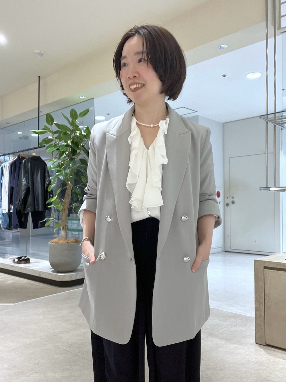 グレー系のテーラードジャケット、ホワイト系のシャツ/ブラウス、ブルー系のスラックスを着用したレディースの冬コーディネートの3枚目の写真