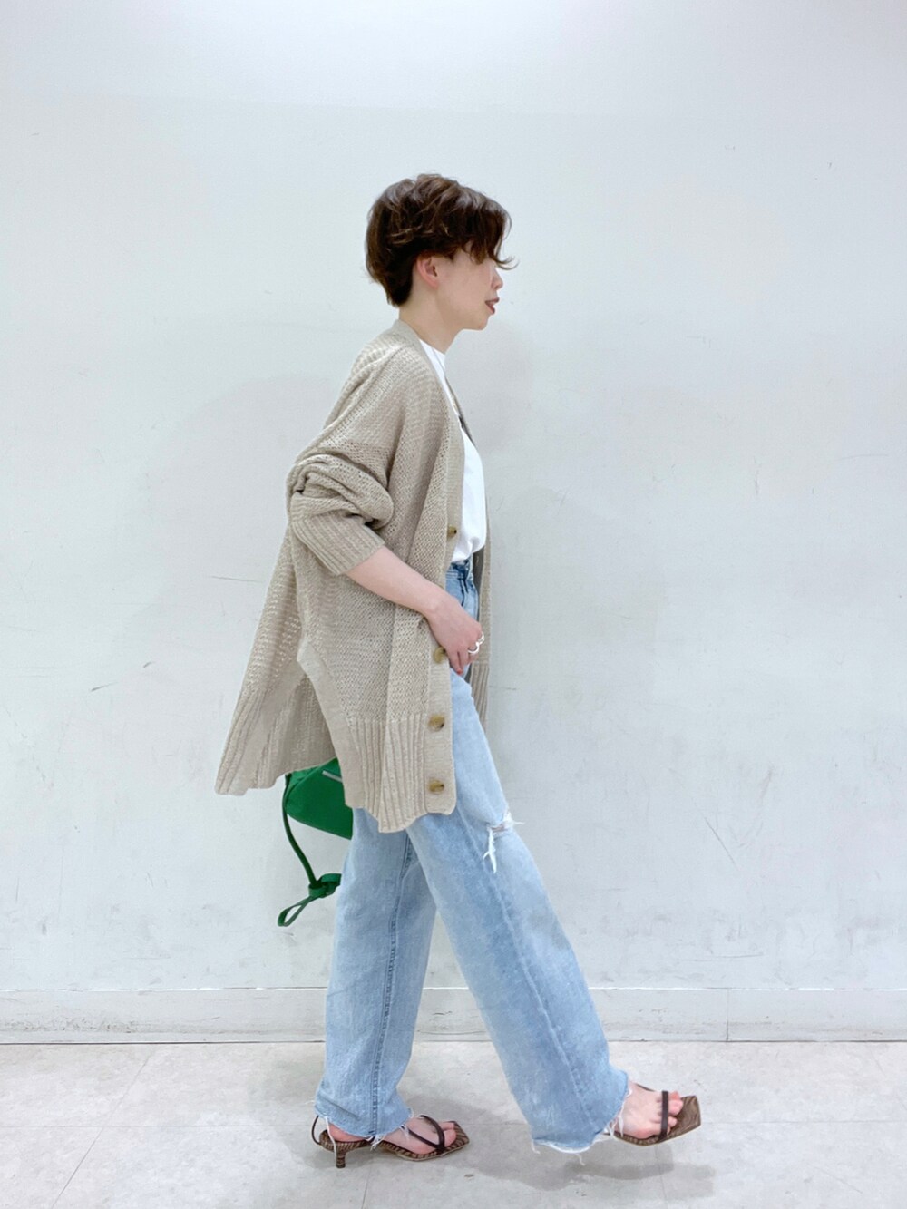 ブルー系のデニムパンツ、ベージュ系のカーディガン/ボレロ、ホワイト系のTシャツ/カットソーを着用したレディースの春コーディネートの2枚目の写真