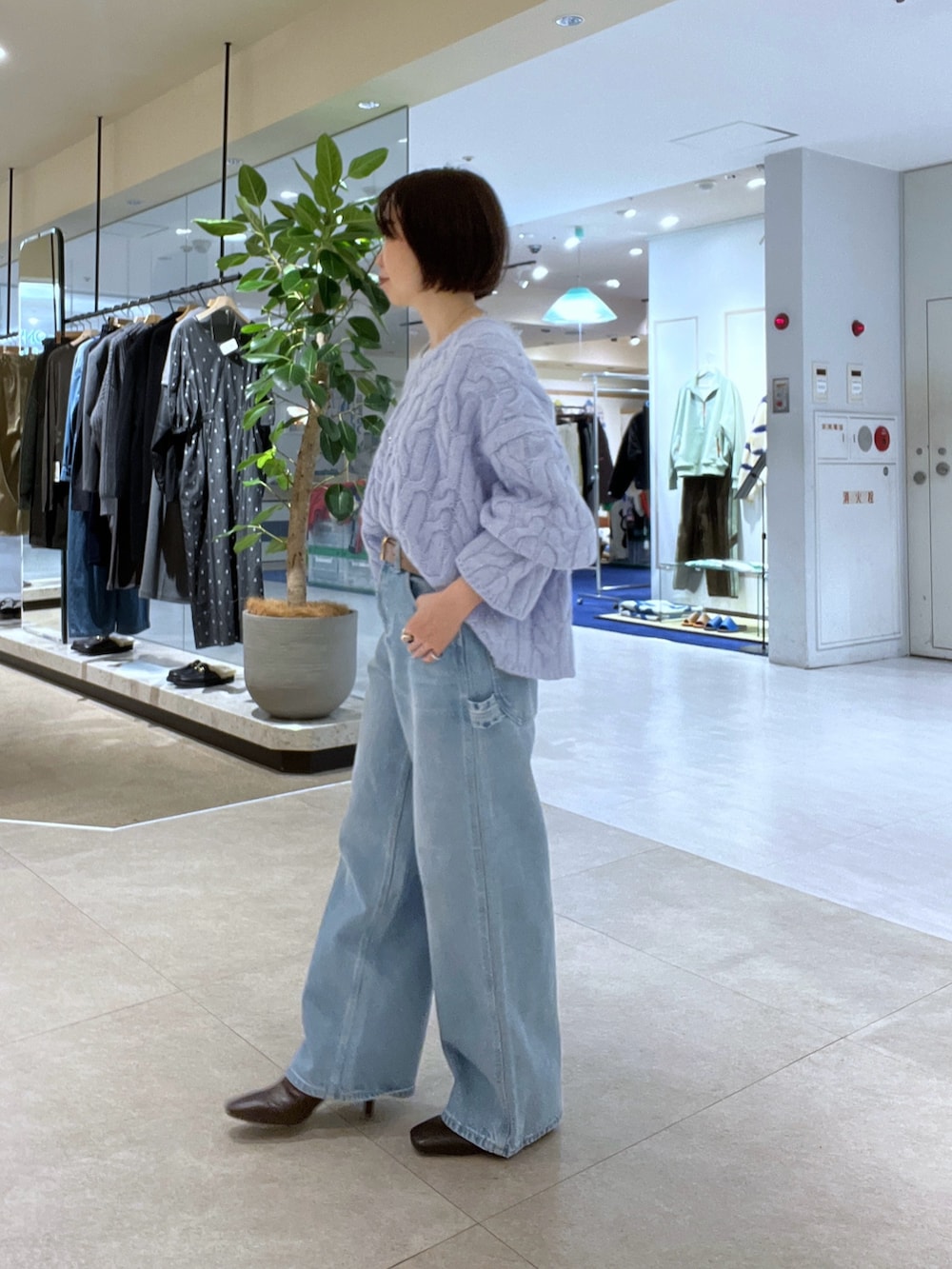 ブルー系のデニムパンツ、ブラウン系のボストンバッグ、ブラウン系のブーツを着用したレディースの秋コーディネートの7枚目の写真