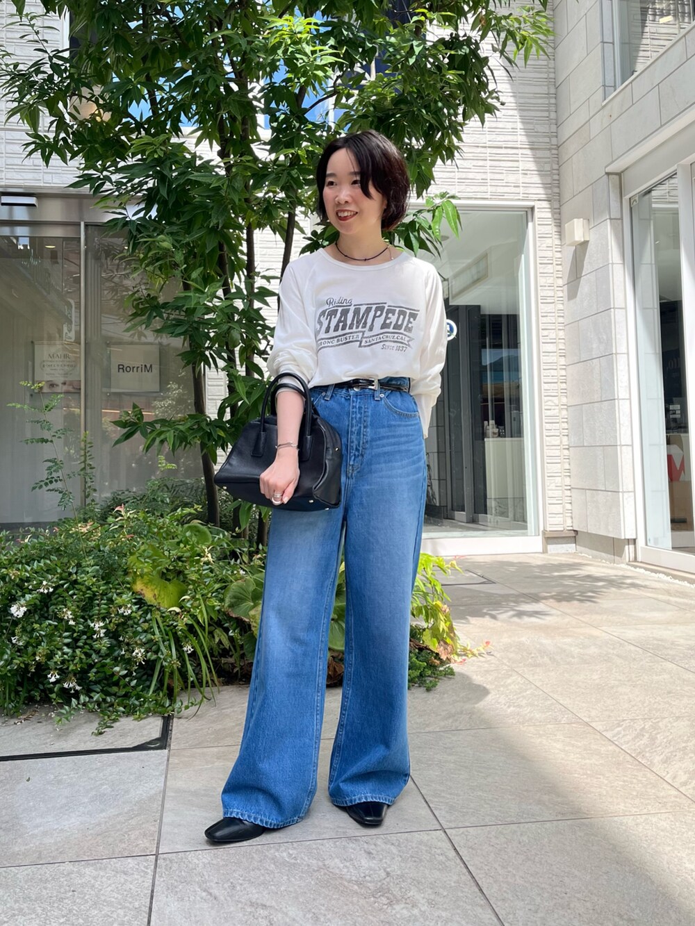 ブルー系のデニムパンツ、ホワイト系のTシャツ/カットソー、ブラック系のボストンバッグを着用したレディースの秋コーディネートの7枚目の写真