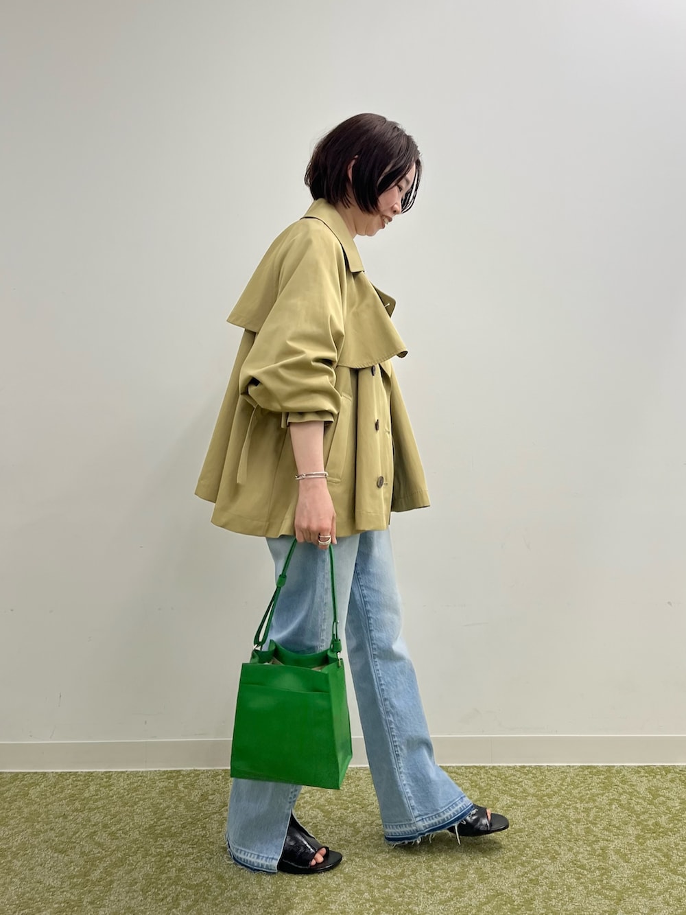 ベージュ系のトレンチコート、ホワイト系のTシャツ/カットソー、ブルー系のデニムパンツを着用したレディースの冬コーディネートの2枚目の写真