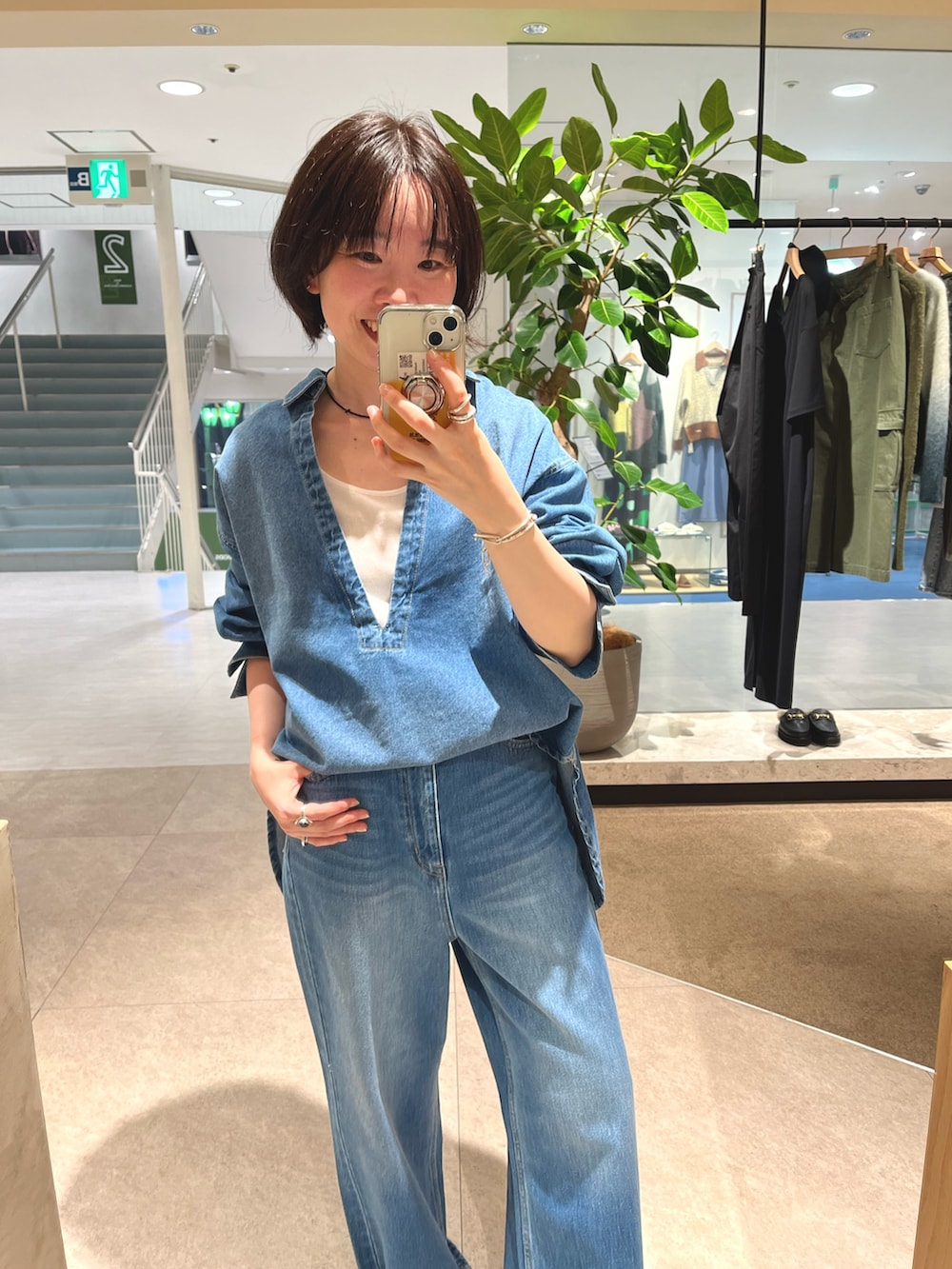 グレー系のステンカラーコート、ブルー系のデニムパンツ、ホワイト系のTシャツ/カットソーを着用したレディースの秋コーディネートの4枚目の写真