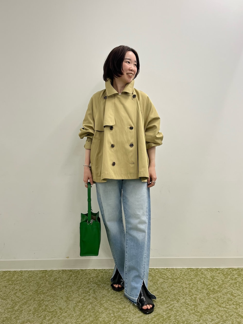 ベージュ系のトレンチコート、ホワイト系のTシャツ/カットソー、ブルー系のデニムパンツを着用したレディースの冬コーディネートの3枚目の写真