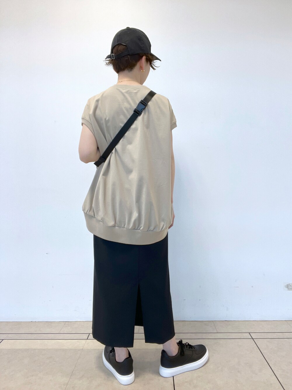 ブラック系のスカート、ベージュ系のTシャツ/カットソー、ベージュ系のボディバッグ/ウエストポーチを着用したレディースの春コーディネートの3枚目の写真