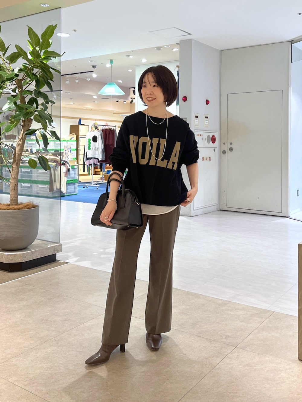 ブラック系のスウェット、ブラウン系のその他パンツ、ブラック系のボストンバッグを着用したレディースの秋コーディネートの7枚目の写真