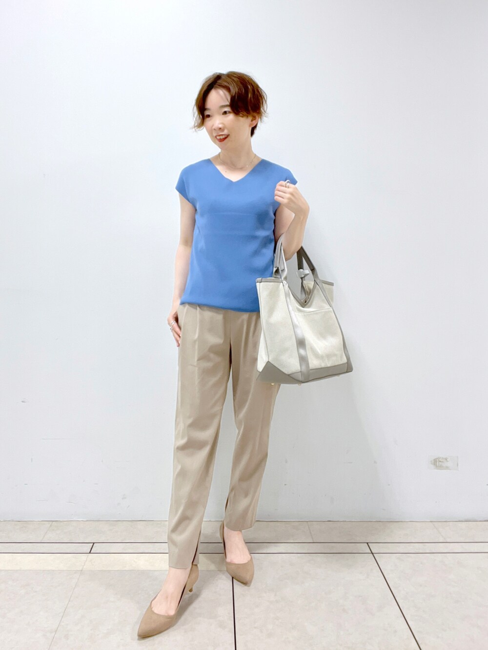 グレー系のトートバッグ、グレー系のカーディガン/ボレロ、ブルー系のニット/セーターを着用したレディースの夏コーディネートの3枚目の写真