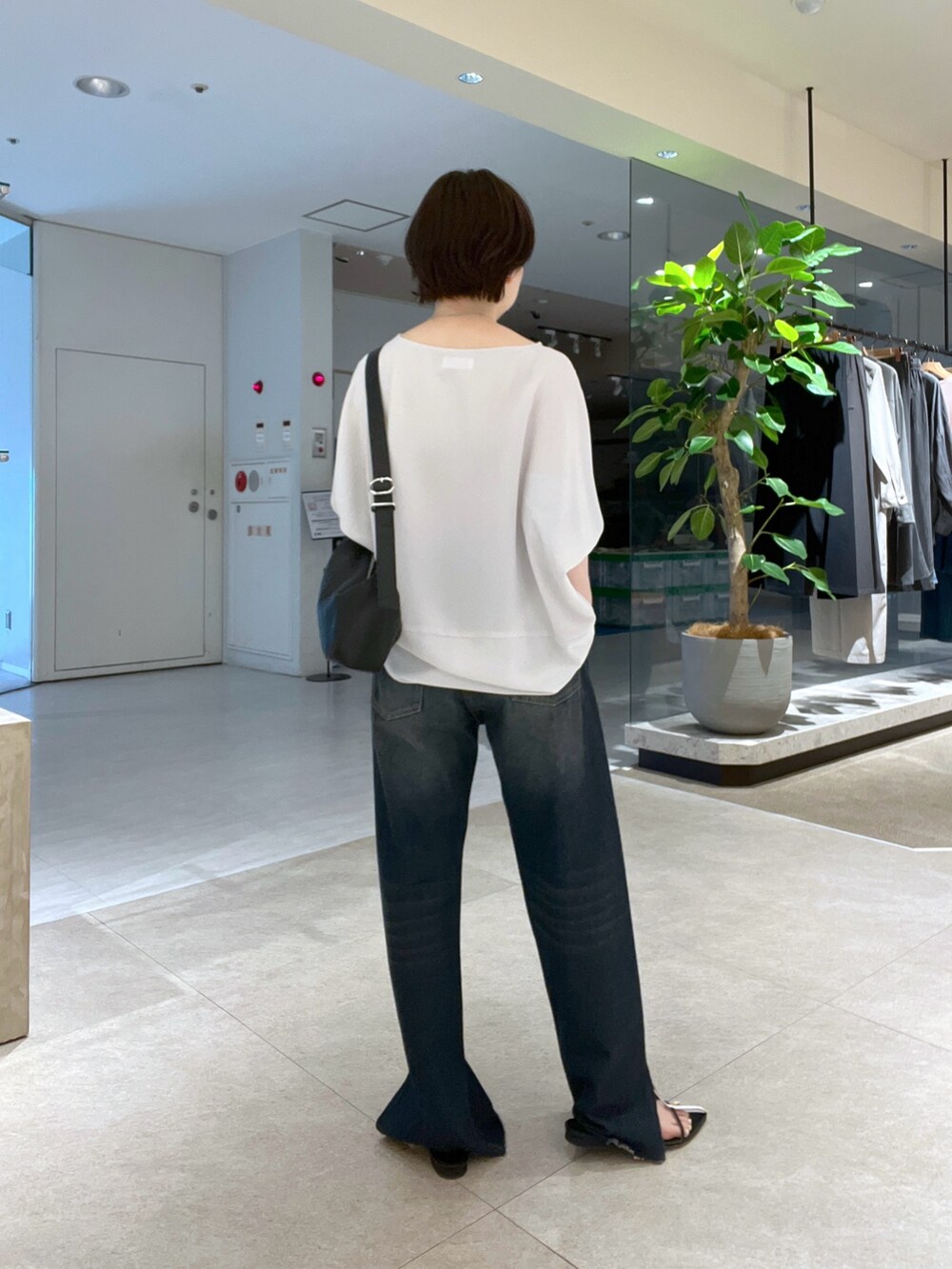 ブルー系のデニムパンツ、ブラック系のハンドバッグ、ブラック系のサンダルを着用したレディースの夏コーディネートの3枚目の写真