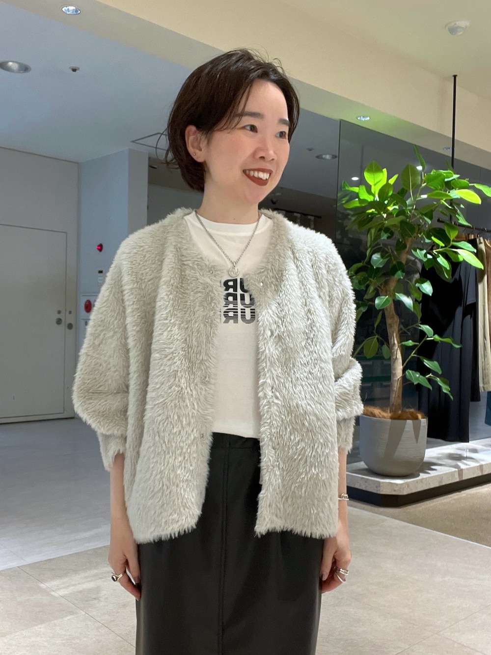 ベージュ系のカーディガン/ボレロ、ブラック系のスカート、ホワイト系のTシャツ/カットソーを着用したレディースの秋コーディネートの4枚目の写真