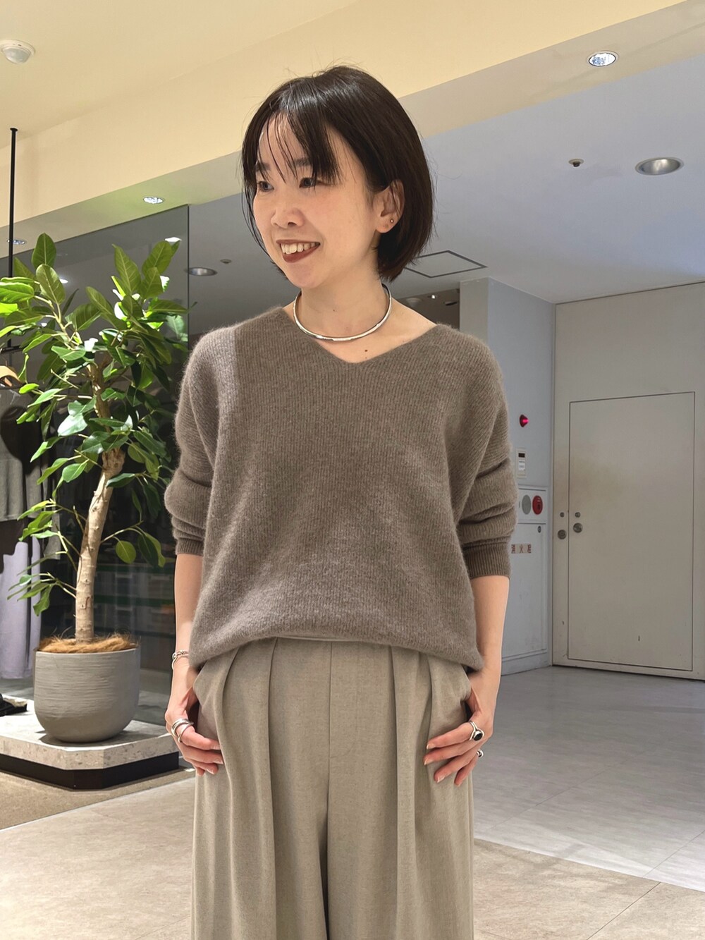 グレー系のニット/セーター、ベージュ系のスラックス、ブラウン系のボストンバッグを着用したレディースの秋コーディネートの6枚目の写真