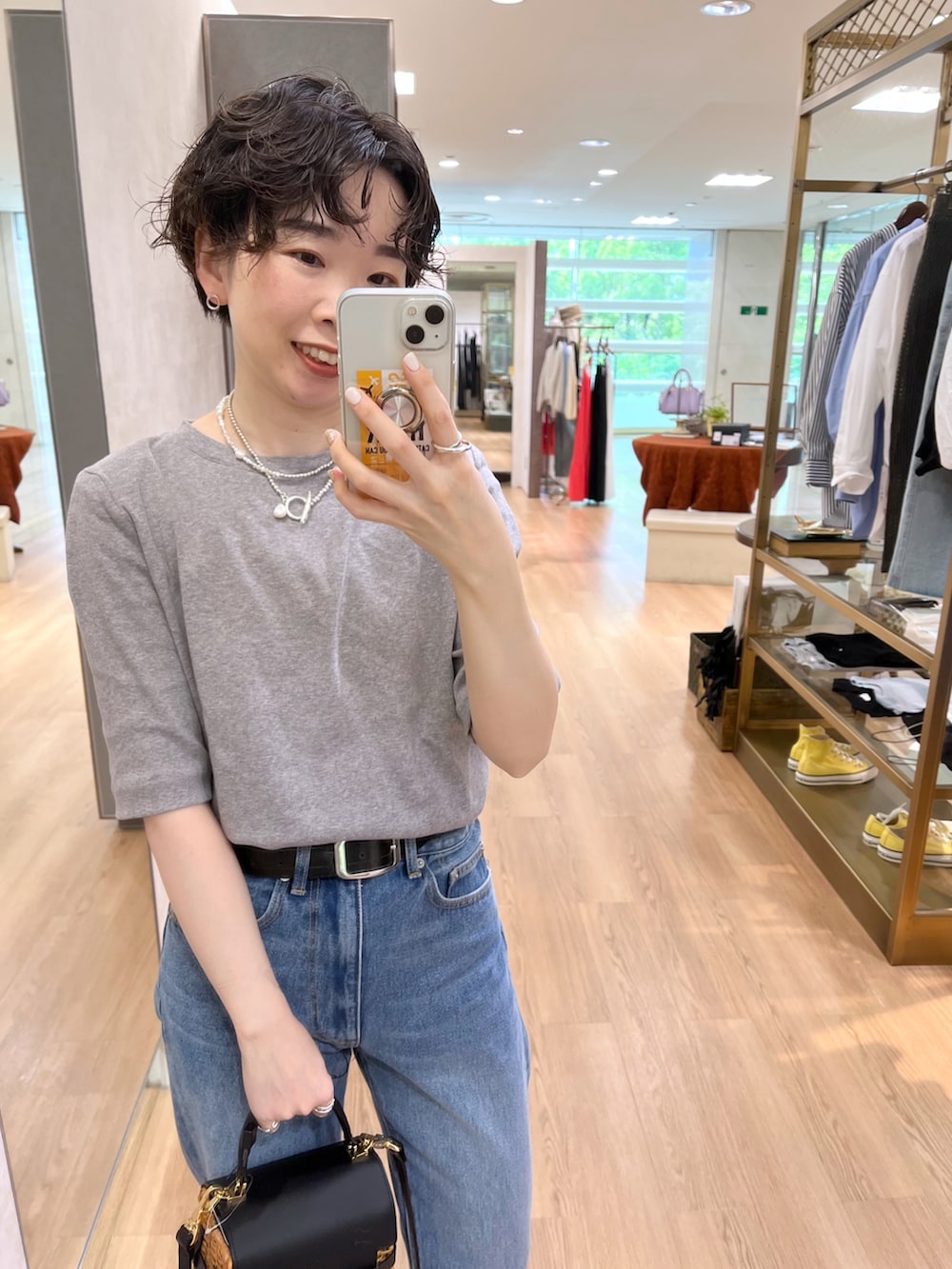 ブラック系のかごバッグ、グレー系のTシャツ/カットソー、ブルー系のデニムパンツを着用したレディースの春コーディネートの3枚目の写真