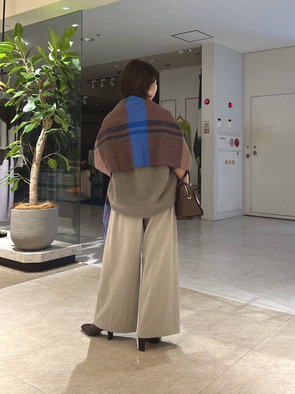 グレー系のニット/セーター、ベージュ系のスラックス、ブラウン系のボストンバッグを着用したレディースの秋コーディネートの3枚目の写真