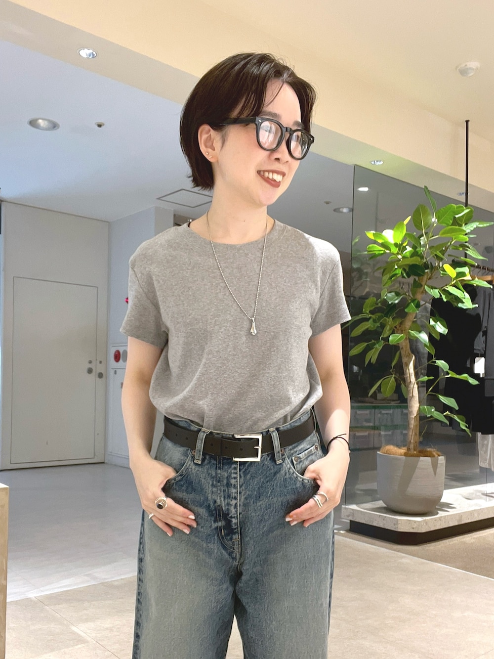 ブルー系のデニムパンツ、ブラック系のサンダル、グレー系のTシャツ/カットソーを着用したレディースの夏コーディネートの4枚目の写真