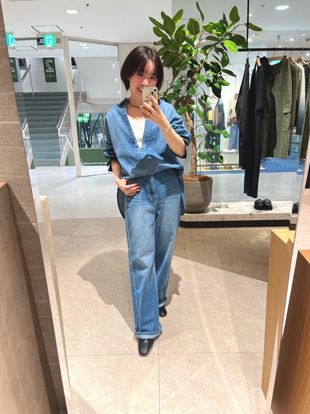 グレー系のステンカラーコート、ブルー系のデニムパンツ、ホワイト系のTシャツ/カットソーを着用したレディースの秋コーディネートの3枚目の写真
