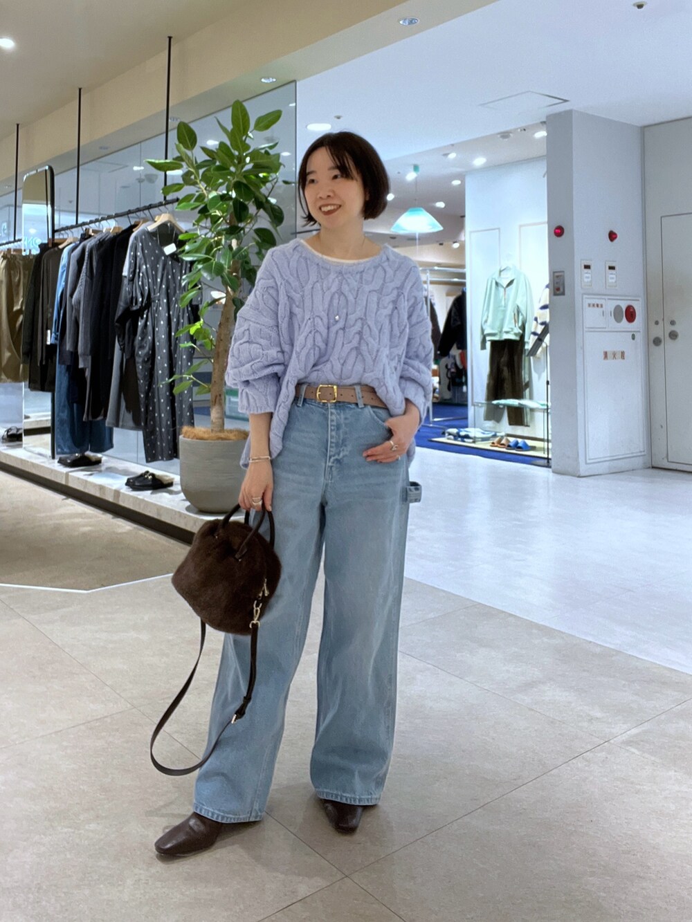 ブルー系のデニムパンツ、ブラウン系のボストンバッグ、ブラウン系のブーツを着用したレディースの秋コーディネートの6枚目の写真