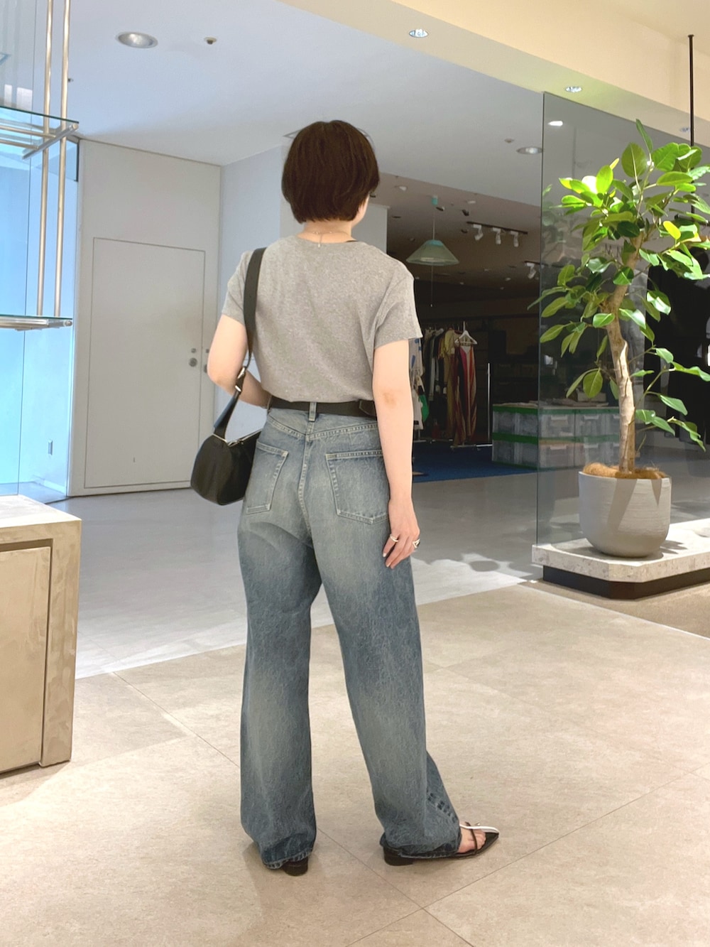 ブルー系のデニムパンツ、ブラック系のサンダル、グレー系のTシャツ/カットソーを着用したレディースの夏コーディネートの3枚目の写真