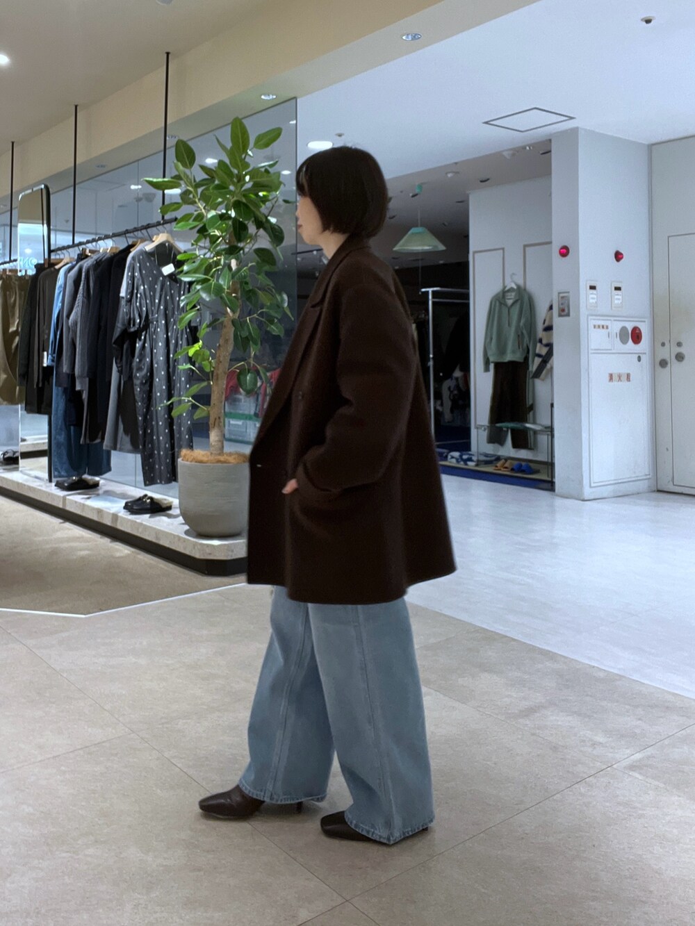 ブルー系のデニムパンツ、ブラウン系のボストンバッグ、ブラウン系のブーツを着用したレディースの秋コーディネートの2枚目の写真