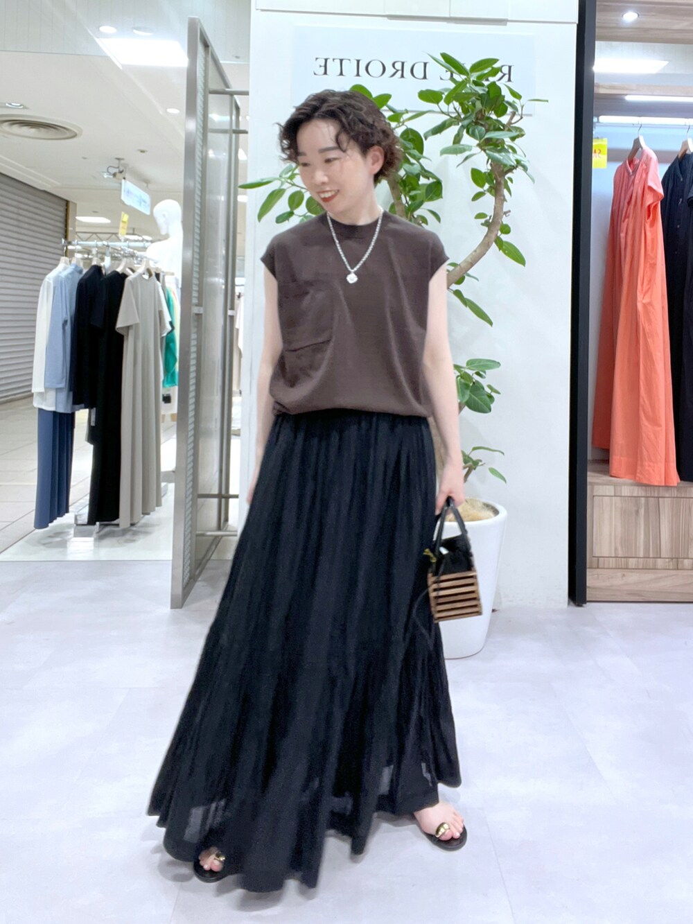 ブラック系のスカート、ベージュ系のシャツ/ブラウス、ブラウン系のニット/セーターを着用したレディースの夏コーディネートの3枚目の写真