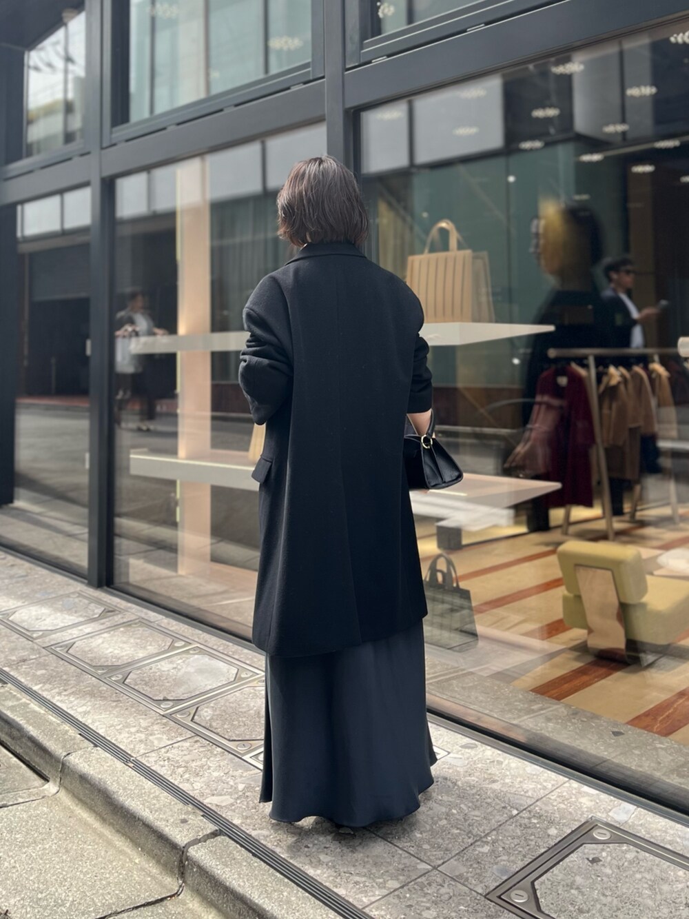 ブラック系のスカート、ブラック系のハンドバッグ、ブラック系のその他アウターを着用したレディースの秋コーディネートの2枚目の写真